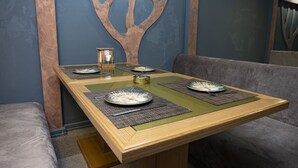 Una mesa de comedor con individuales, platos y cubiertos, frente a una pared azul con un diseño similar a un árbol.