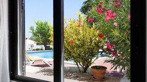 A window view of a swimming pool, a potted plant, and a building in the background. - Apartment 'A Cerca - A' close to the Beach with Shared Pool & Wi-Fi (Lagos)