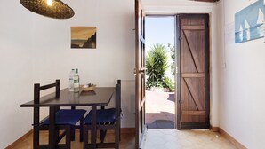 A dining area with a table and chairs, a hanging light fixture, a door leading outside, and a wall-mounted picture. - Apartment 'A Cerca - A' close to the Beach with Shared Pool & Wi-Fi (Lagos)
