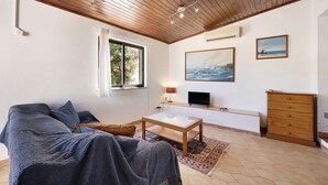 A living room with a wooden ceiling, a sofa, a coffee table, a TV, a dresser, and a painting on the wall. - Apartment 'A Cerca - A' close to the Beach with Shared Pool & Wi-Fi (Lagos)