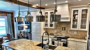 Una cocina con encimera de granito, electrodomésticos de acero inoxidable y armarios blancos.