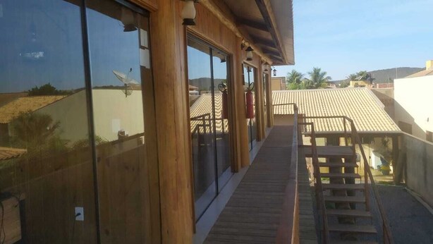Un edificio de madera con amplias ventanas y una terraza de madera que conduce a un espacio cubierto con techo.