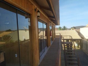Un edificio de madera con amplias ventanas y una terraza de madera que conduce a un espacio cubierto con techo.