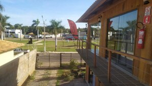 Hotel con fachada de madera, balcón y vistas del entorno, incluyendo una bandera y un extintor.