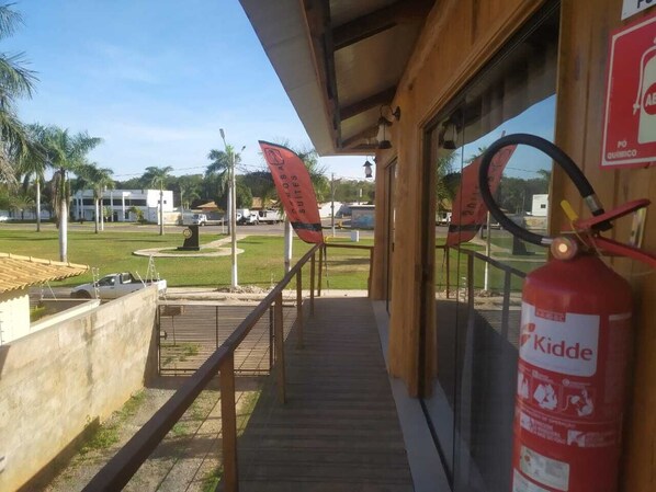 Entrada de un hotel con una terraza de madera, un extintor y un letrero de 'Kidde' en la pared.