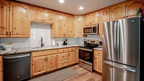A kitchen with wooden cabinets, stainless steel appliances, a microwave, oven, and a dishwasher.