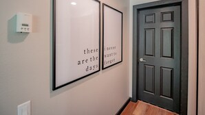 A hallway with two framed quotes on the wall and a thermostat on the left.