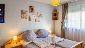 A neatly made bed with pillows, a bedside lamp, and wall art.