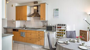 A compact kitchen with wooden cabinets, a microwave, and a wine rack.