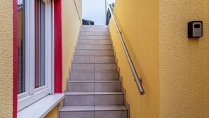 A staircase with a handrail, a window with white frames, and a textured yellow wall. - Holiday Apartment "Im Bubenstück" with Wi-Fi (Bingen)