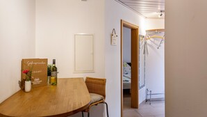 A room with a wooden table, a wicker chair, a bottle of wine, a signboard, and a bed in the background. - Holiday Apartment "Im Bubenstück" with Wi-Fi (Bingen)