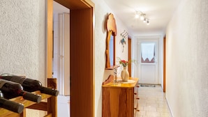 Un corridoio con porte in legno, una dispensa per vino in legno, un vaso con fiori e un appendiabiti.