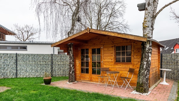 Una baita in legno con un patio, un tavolino e due sedie.