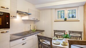 Una cucina con forno a incasso, lavello e finestra sopra il tavolo da pranzo.