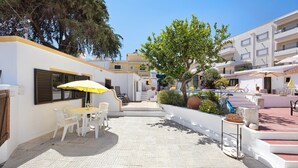 Un patio con mesas al aire libre, un árbol y un edificio con balcones.