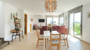 Amplia sala de estar con mesa de comedor, sillas, sofá y un gran ventanal con vistas.
