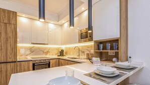 Une cuisine moderne dotée d’un îlot central, d’un four à micro-ondes encastré et de meubles de rangement en bois.