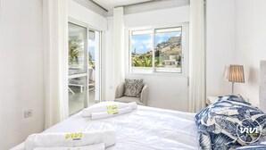 Une chambre d’hôtel avec un lit, une chaise, une lampe et une vue sur l’extérieur.