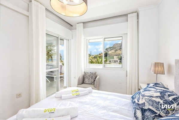 Una habitación de hotel con una cama, una ventana con vistas, una silla y una lámpara.