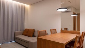 Un salon moderne avec une table à manger en bois, un canapé beige et un grand miroir.