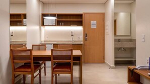 Une cuisine moderne avec un coin repas, des meubles en bois, un four à micro-ondes et un évier.