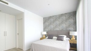 A bedroom with a bed, nightstands, and a wardrobe. - 2202 Modern Apartment with Panoramic Sea Views (Cancelada Estepona)