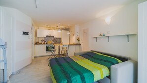 Une chambre compacte comprenant un lit, une petite kitchenette et une salle de bain.