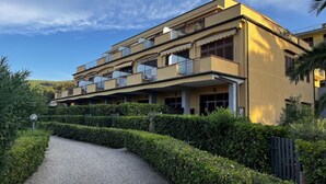 Un immeuble à plusieurs étages doté de balcons, d’un chemin de gravier et de haies bien entretenues.