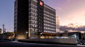 A modern hotel with a prominent 'ibis' sign, multiple floors, and a parking area with cars. - Ibis Botucatu (Botucatu)