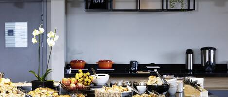 A modern kitchen with a black countertop, various food items, and a sign that reads "ibis".