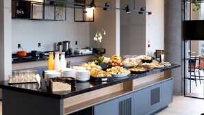 A modern breakfast buffet with a variety of food items and beverages, a coffee station, and a seating area with chairs and a table. - Ibis Botucatu (Botucatu)