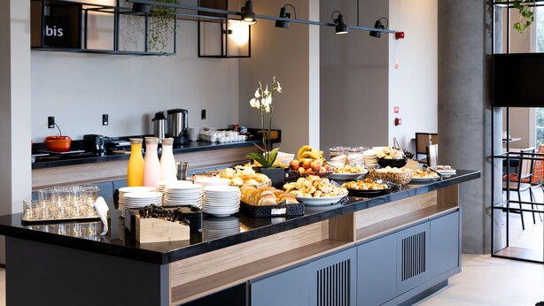 A modern breakfast buffet with a variety of food items and beverages, a coffee station, and a seating area with chairs and a table. - Ibis Botucatu (Botucatu)