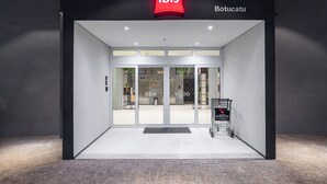 A modern hotel entrance with a glass door, a visible reception area, and a sign indicating the name "ibis Botucatu". - Ibis Botucatu (Botucatu)