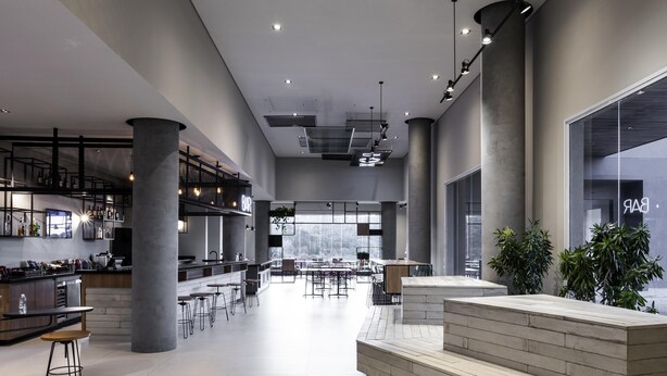 A spacious bar area with high ceilings, modern lighting, and a view of the outdoors. - Ibis Botucatu (Botucatu)