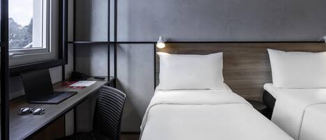 Habitación de hotel con escritorio, dos camas, ventana y vistas al exterior.