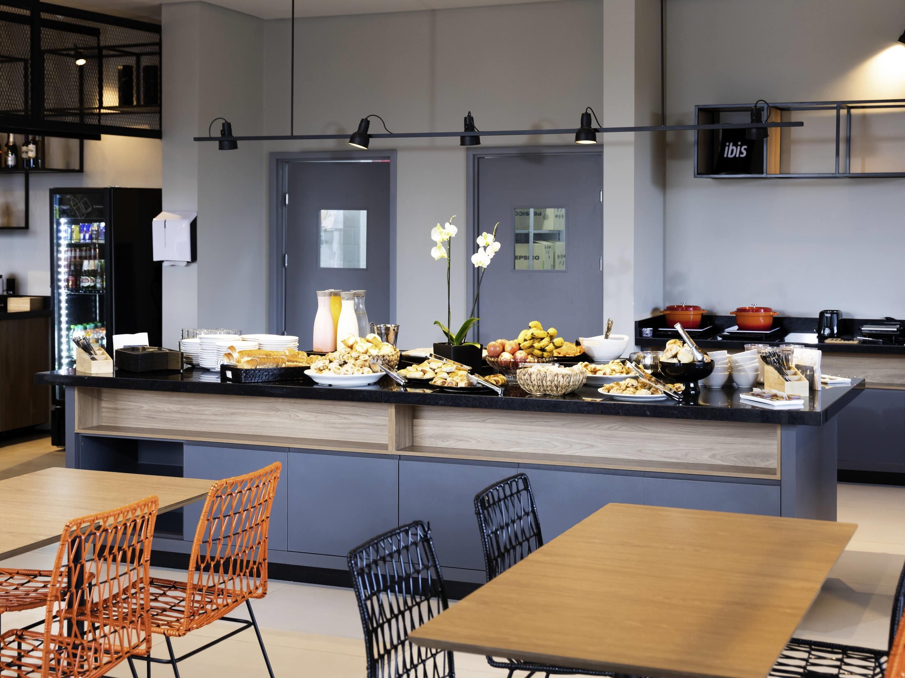 A modern kitchen with a central island, buffet setup, and seating area.