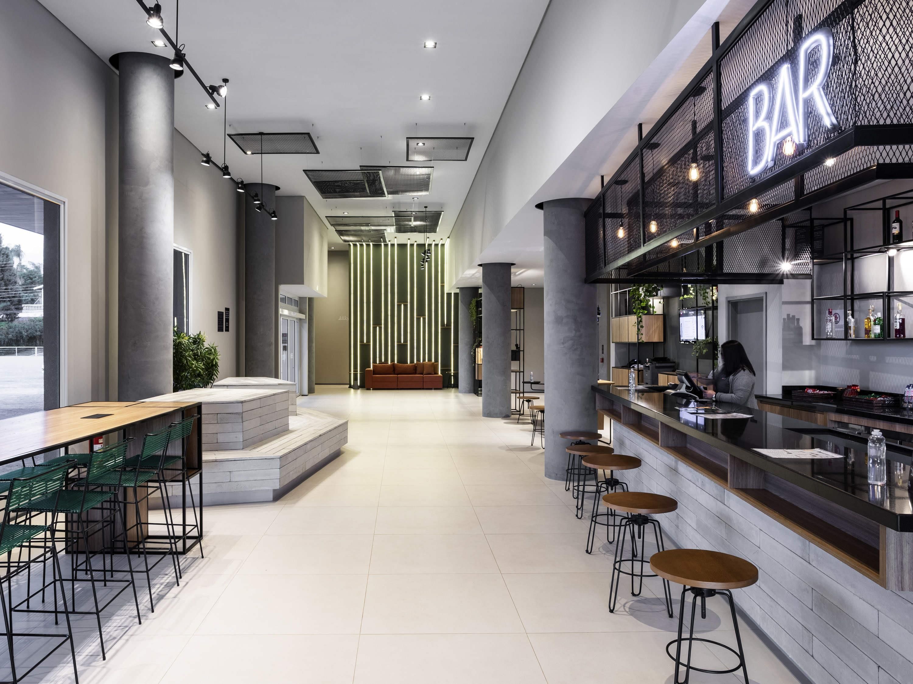 A modern bar area with a bar counter, stools, and a seating area with tables and chairs.