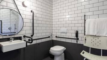 Casa de banho moderna com azulejos brancos tipo metrô, sanita branca, lavatório com espelho e um porta-toalhas.