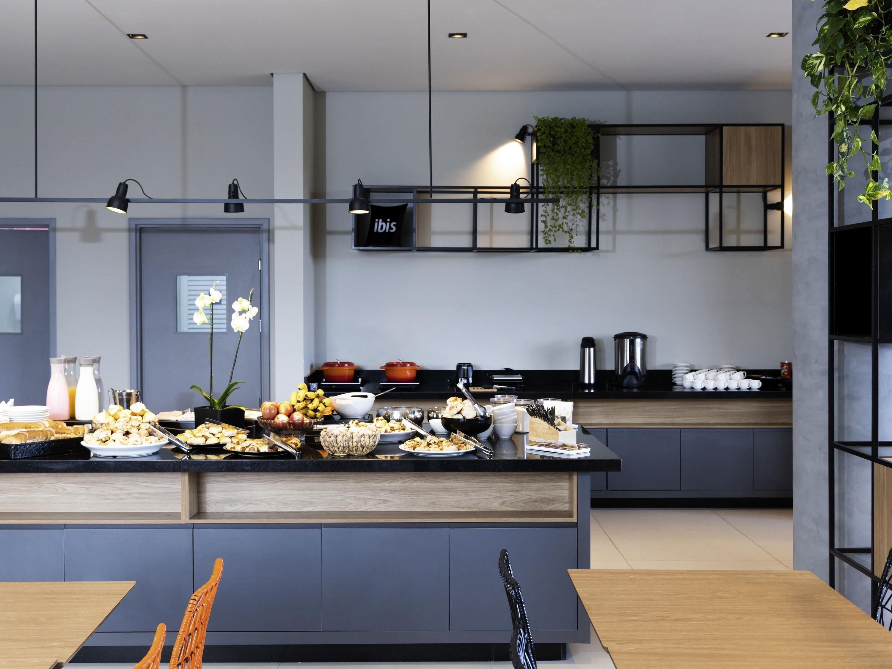 A modern kitchen with a central island, various food items, and a hanging plant.