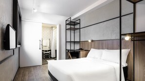 A modern hotel room with a bed, a desk, and a shower area. - Ibis Botucatu (Botucatu)