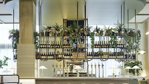A bar area with a curved seating arrangement, a wine display, and hanging plants.