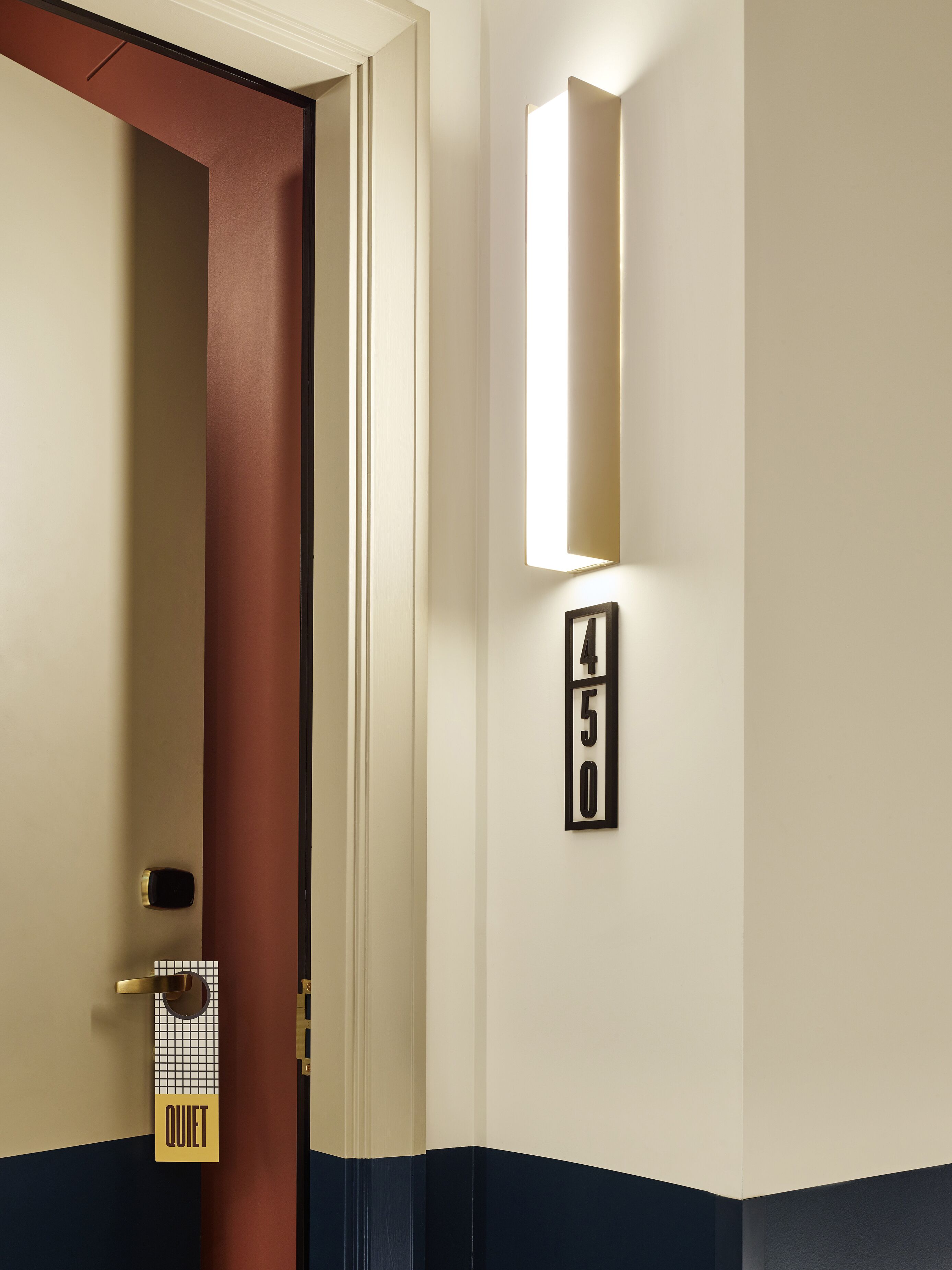 En hotelværelses indgang med en dør, et skilt med teksten 'QUIET' og et fastgjort nummer '450'.
