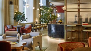 Een moderne lounge met zithoek, een bar en grote ramen voor veel daglicht.