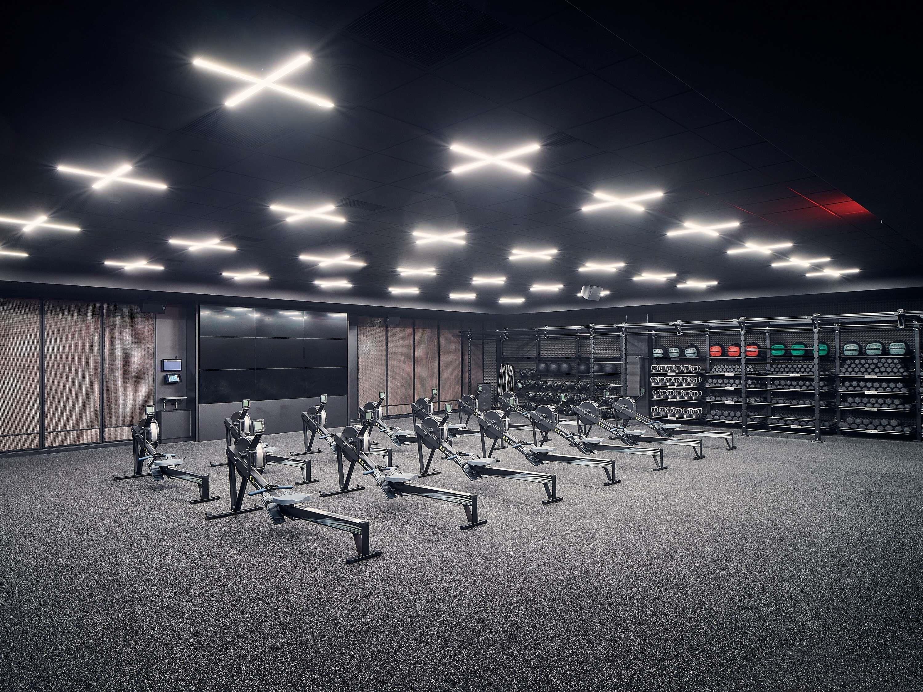 A gym with rowing machines and weight racks.