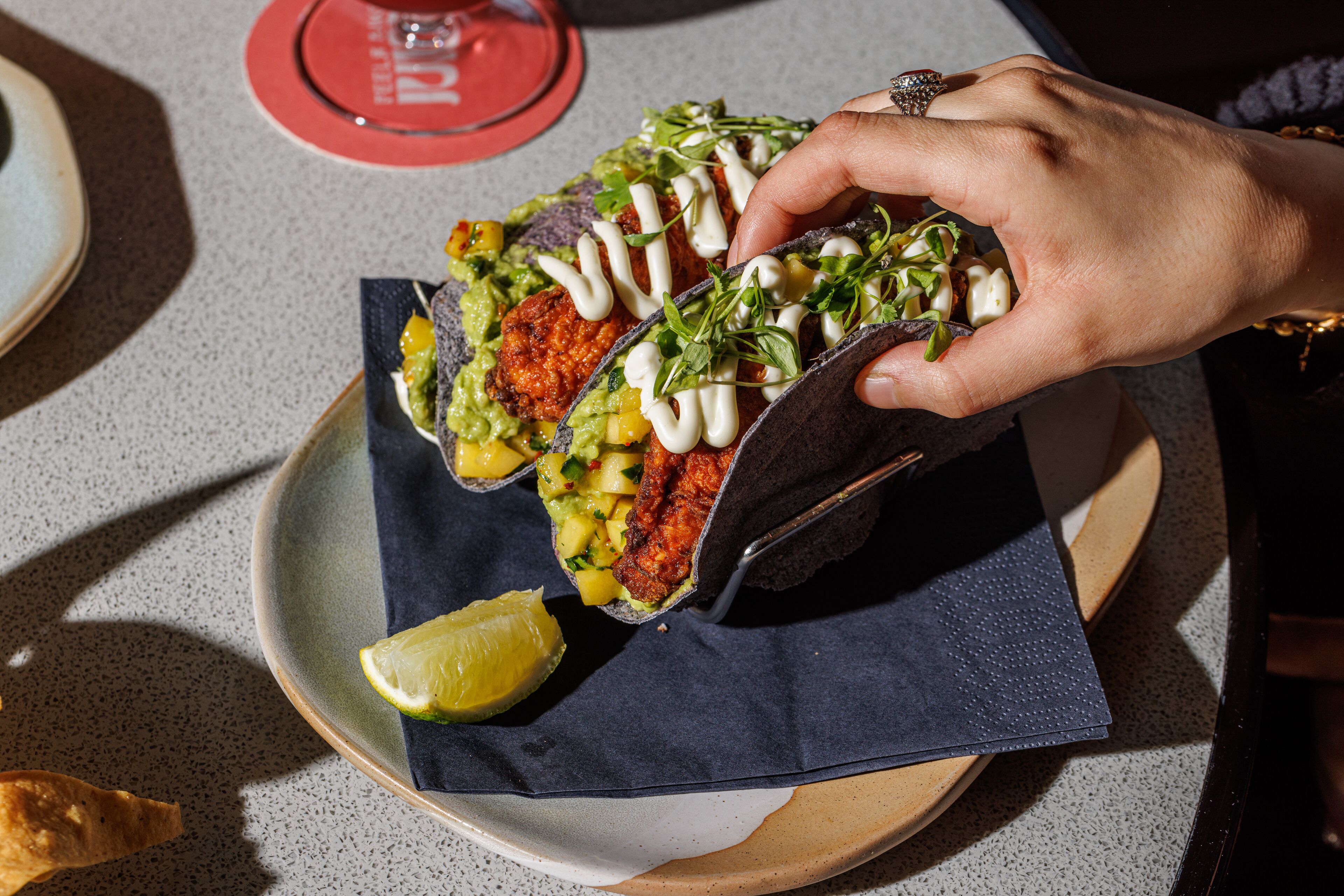 A person holding a wrap with a lime wedge on a plate.
