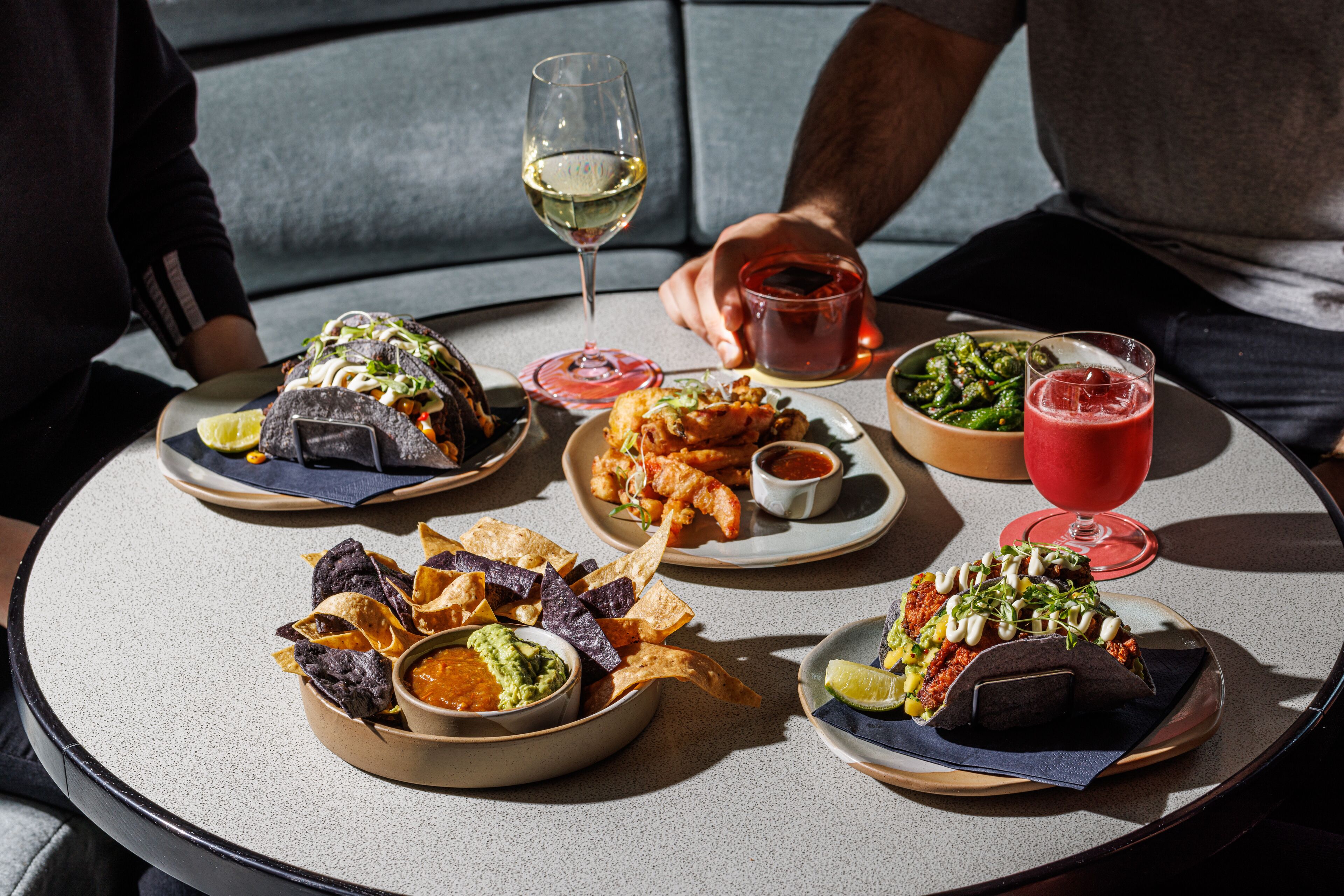 Ein Tisch mit verschiedenen Speisen und Getränken, darunter Tacos, ein Salat und ein rotes Getränk.