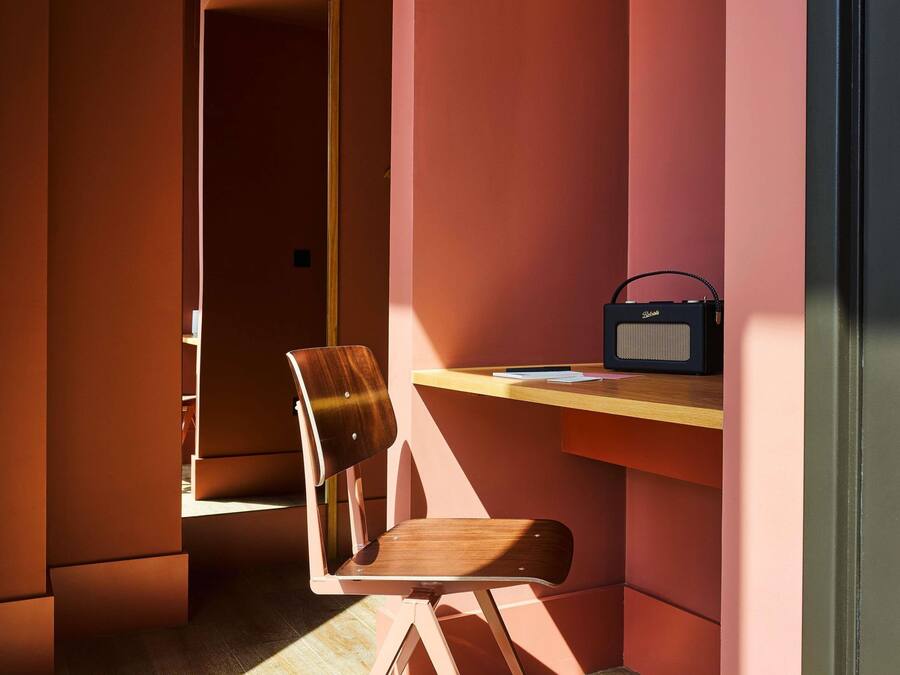 A room with a wooden chair, a desk, and a radio.