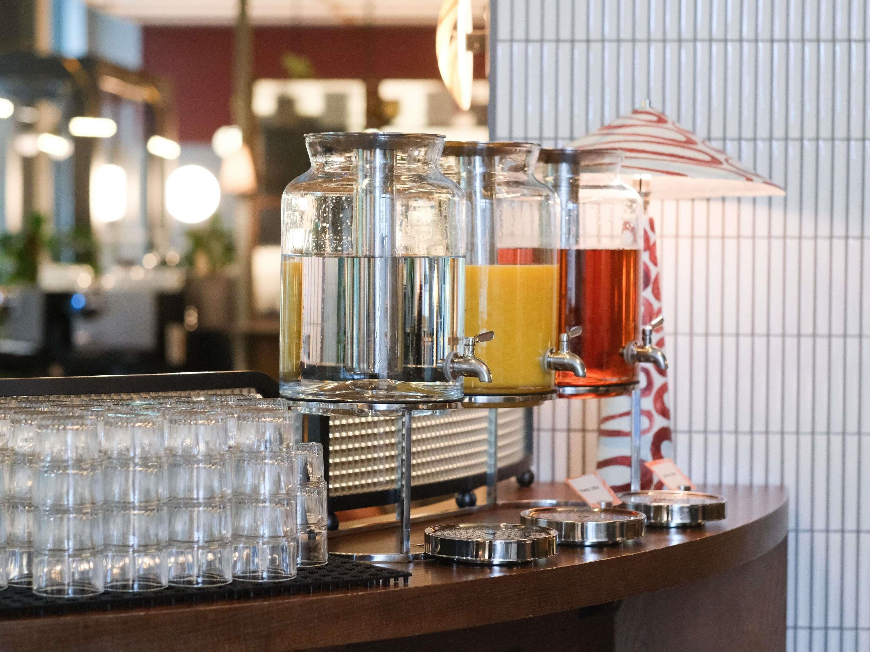 Una zona de bar con varios dispensadores de bebidas y una pila de vasos.