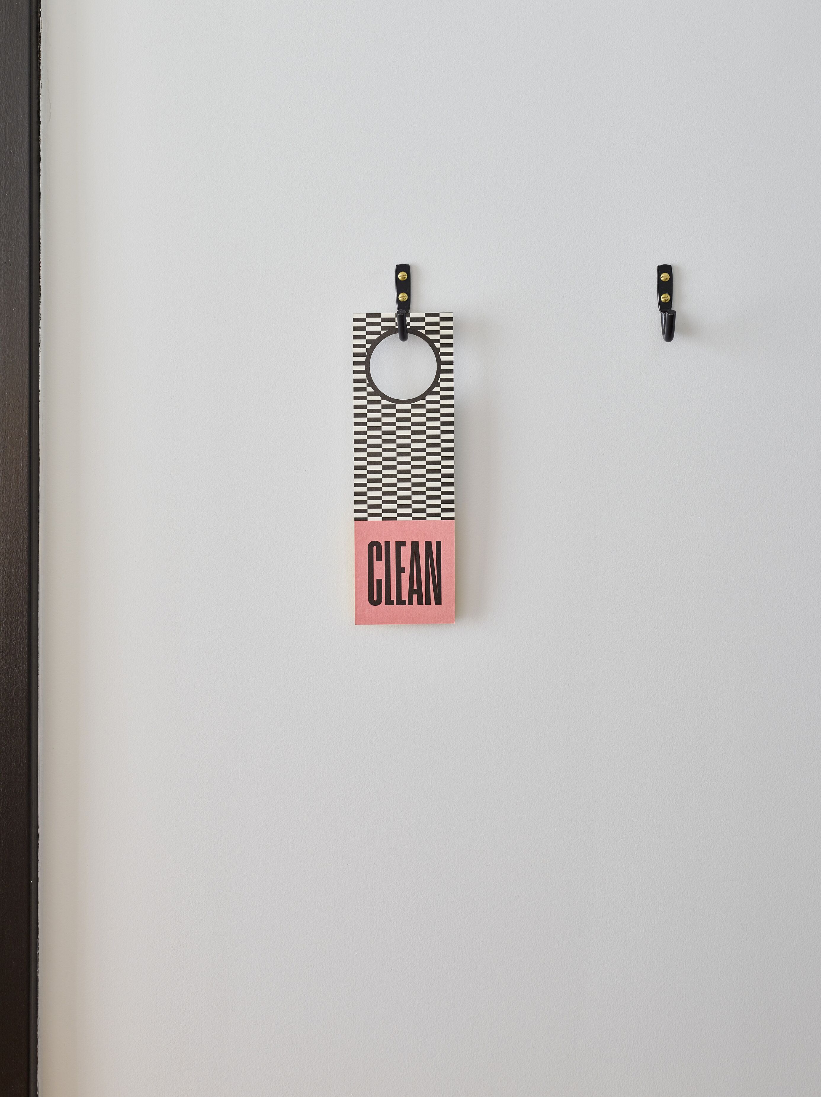Paredes com uma etiqueta pendurada que diz "CLEAN" e um batente de porta.