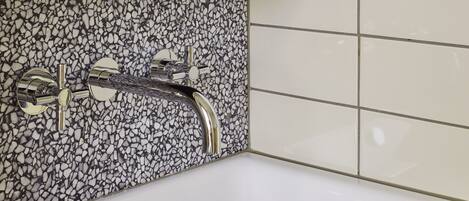 A bathroom with a white sink, a modern faucet, and a tiled backsplash.